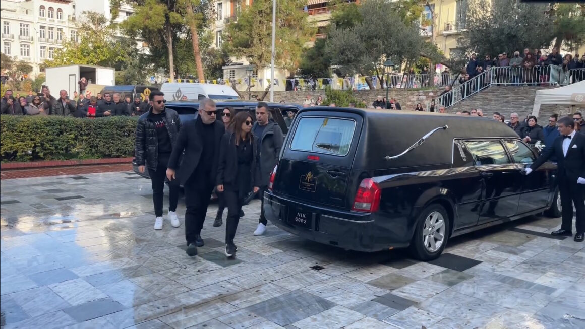 Βασίλης Καρράς: Η στιγμή που η σύζυγος και η κόρη του συνοδεύουν το φέρετρο στην εκκλησία – 30 λεωφορεία από Αθήνα για να αποτίσουν τιμές